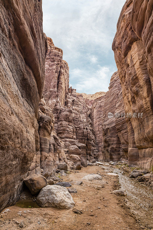 A shallow  stream flows between rocks painted with intricate natural patterns at start of the Wadi Numeira walking trail in Jordan